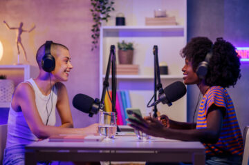Two happy gen z multiracial girls are sitting in a home broadcasting studio Two happy gen z multiracial girls are sitting in a home broadcasting studio