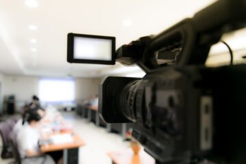 video camera in business conference room recording participants and headphone video camera in business conference room recording participants and headphone